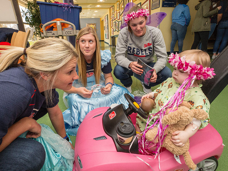 Ole Miss softball players, from left, Kaitlin Lee, Alex Schneider and Brittany Finney share princess finery with Batson Children's Hospital patient Emma Grace Simpson of Hattiesburg.