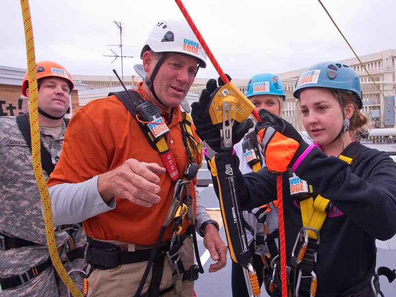 Chris Davis coaches Mary Ellis Cravey, a former Batson Children's Hospital patient and leukemia survivor, on rappelling just before she descended 14 stories from the top of the Trustmark building in Over The Edge with Friends, a fundraiser for Friends of Children's Hospital. Looking on are Mississippi National Guard Master Sgt. Mike Callaghan and Child Life specialist Tiffany Key.