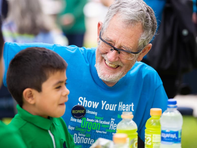 Charlie Crane, right, of Clinton, shares a laugh with fellow donor organ recipient Ander Serano, 5, of Canton, at Friday's Legacy lap as Ander's father, Fausto Serano, left, looks on.