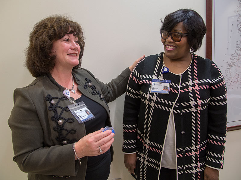 Henderson, left, presents a commendation pin to Cecelia Bass, director of employee relations.