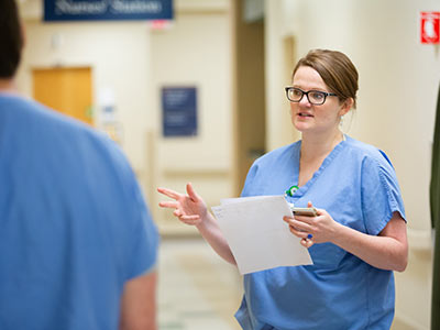 Dr. Meagan Mahoney confers with one of her colleagues near a nurses' station.