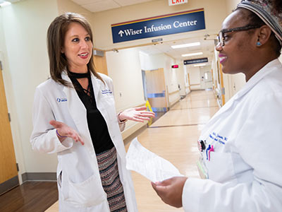 Dr. Rachel Riley, left, a recent OB-GYN residency graduate, has a collegial word with current resident Dr. Solita Jones.