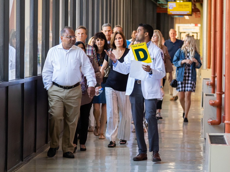 Second-year medical student Aalaap Desai leads tour group participants toward their next stop: the Gross Anatomy Lab.