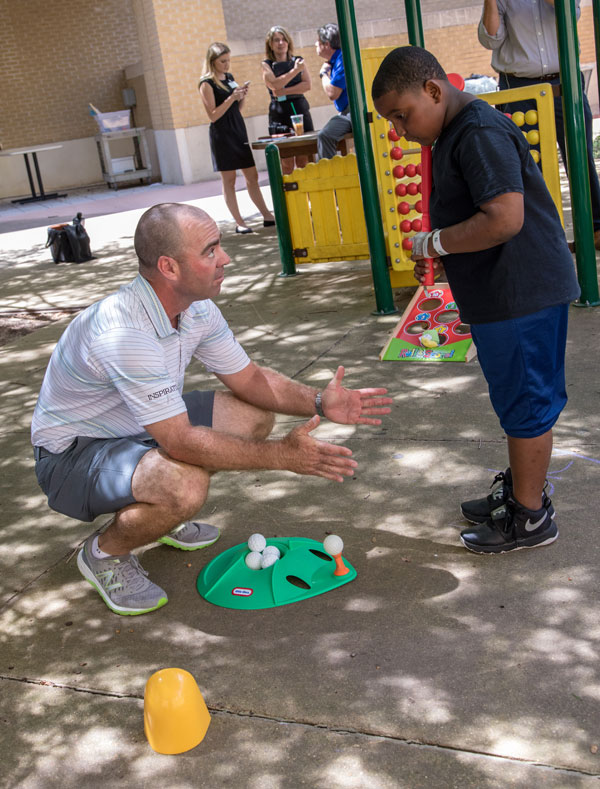 Armour gives tips on golfing to Batson Children's Hospital patient Aiden Moore of Forest.