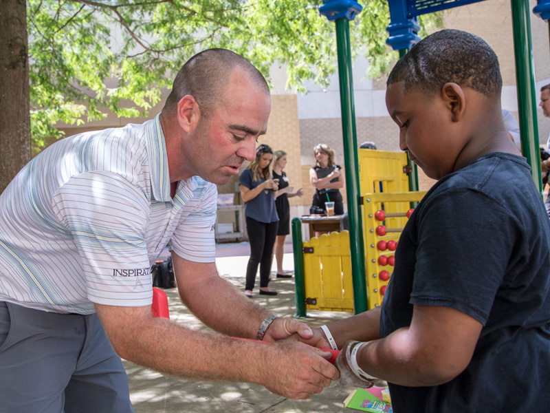 Armour shows Batson Children's Hospital patient Aiden how having the right grip makes golfing easier.