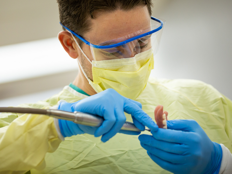 Kyle Walker, a third-year dental student, makes adjustments to dentures to ensure they fit correctly.