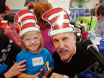 Ryleigh Sayers smiles with John Anthony of Mix 98.7 during a Mississippi Miracles Radiothon.