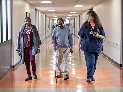 Registered nurse and cardiology care coordinator Stephanie Teague, right, walks with mitral valve patients Julia Ann Flowers and Lucious Thomas.