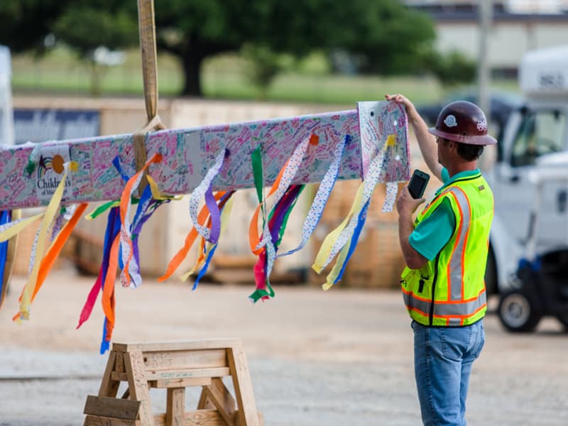 A beam covered with streamers and signatures is prepared for being lifted to the top of UMMC's seven-story pediatric expansion.