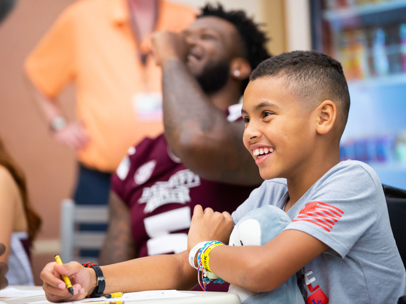 Patient Johannon Payne of Pontotoc smiles while drawing pictures with the Mississippi State football team.