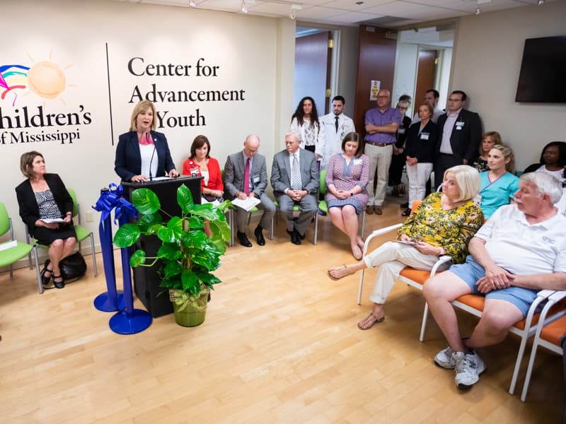 Dr. LouAnn Woodward, vice chancellor for health affairs and dean of the School of Medicine, welcomes attendees to a ribbon-cutting for the new location of the Center for Advancement of Youth.