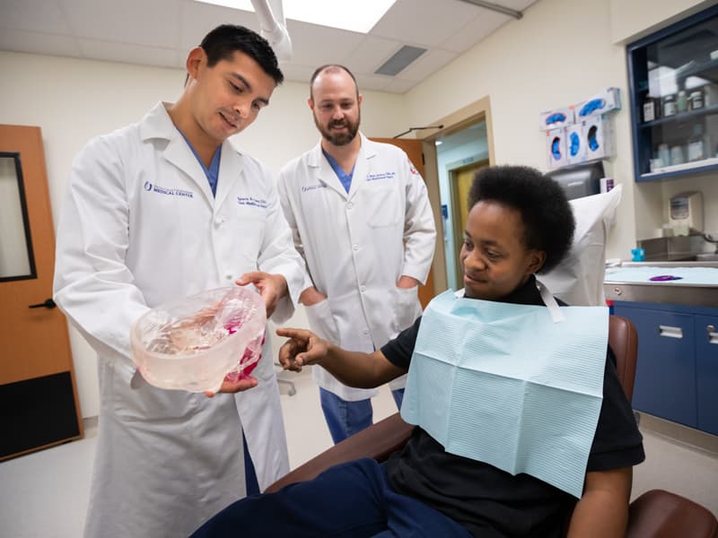 Dr. Ignacio Velasco Martinez, left, talks with his patient, Violet Thompson, right, while Dr. James Jackson observes.