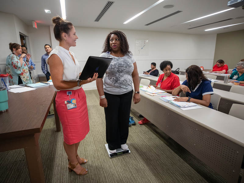 Dr. Abigail Gamble, left, assistant professor of preventive medicine, weighs in Pam Greenwood. a Human Resources service partner, during a diabetes prevention class.