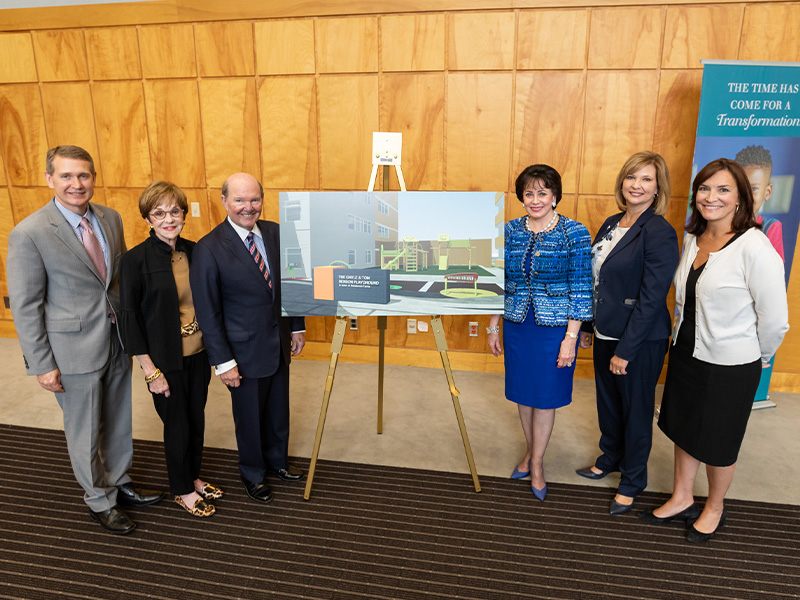 Group stands with artist rendering of playground.