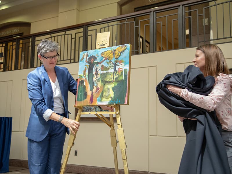 Artist Ellen Langford, left, and Skye Stoker, director of UMMC's Office of Patient Experience, unveil Langford's painting, "All of This," which celebrates Frances Anne Fortner's "zest for life."