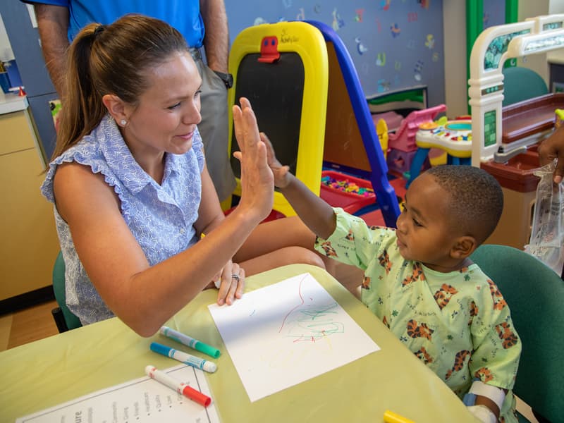 Children's of Mississippi patient Jayceston Harris of Waynesboro gives a high five to Ashley Teater, wife of Sanderson Farms Championship golfer Josh Teater.