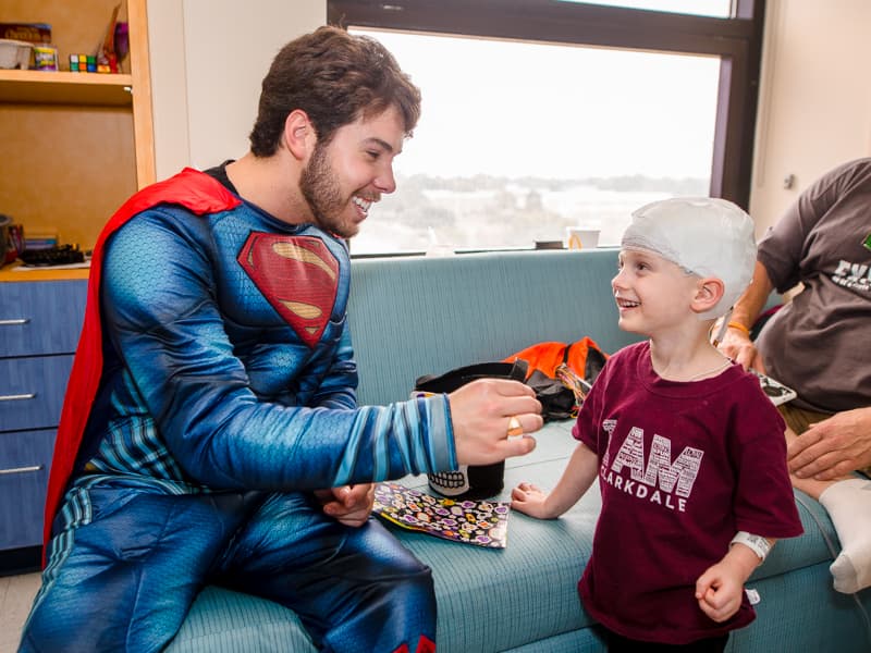 Children's of Mississippi patient Paxton Rogers of Pelahatchie gets Halloween stickers from Superman, aka PediaRebs member Gaston Box.