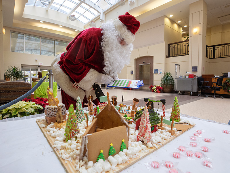 Santa Claus examines details on a gingerbread house during the 2018 Gingerbread Village Competition.
