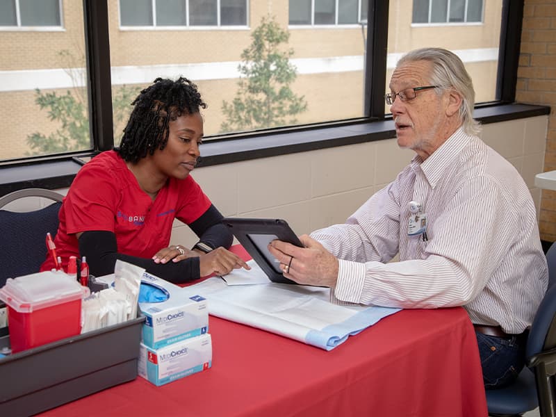 Woman, left, looks on as a man signs up for the Biobank program.