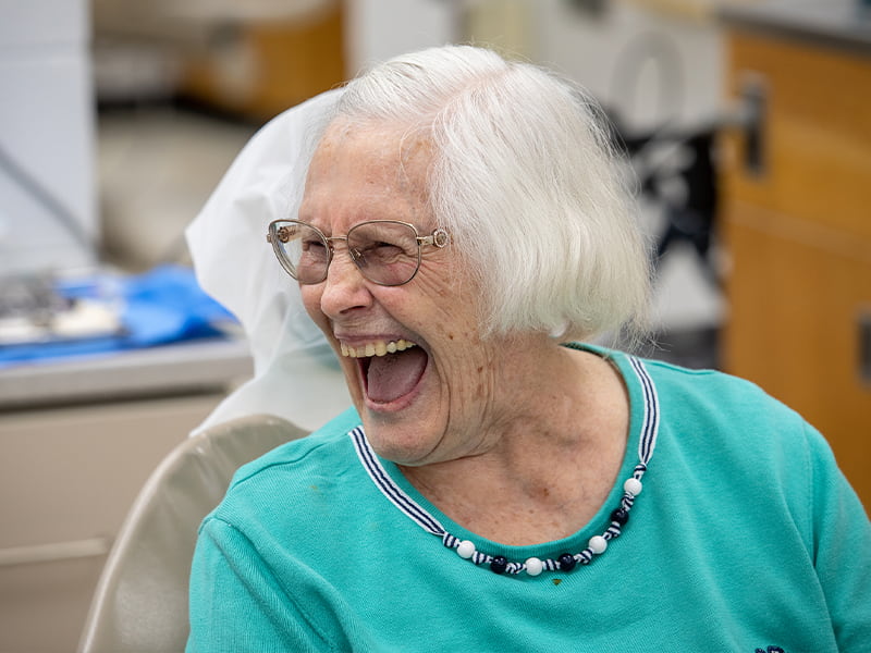 Dental patient laughs while talking to someone off camera.