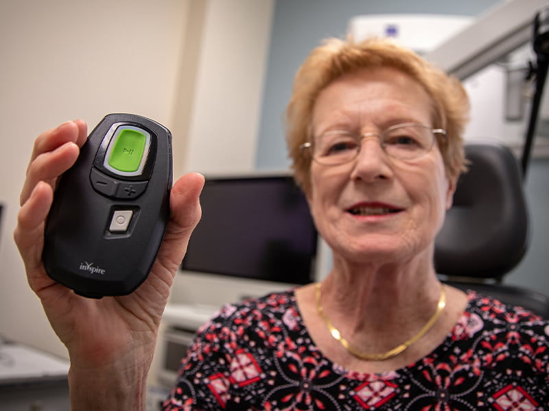 Patient holds out the remote control that opens her airway. 