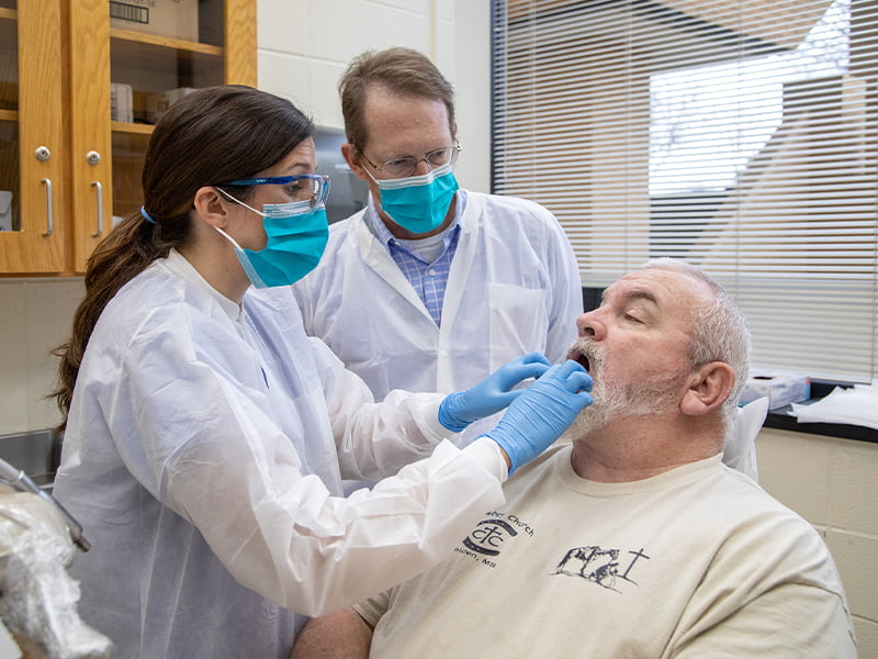 Two dentists check a patients mouth.