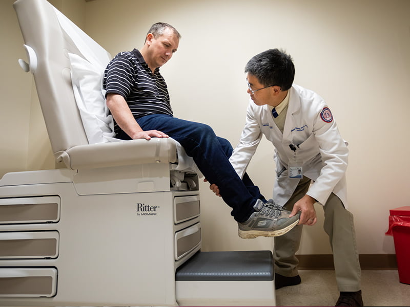 Doctor holds patients foot during a motor skills test.