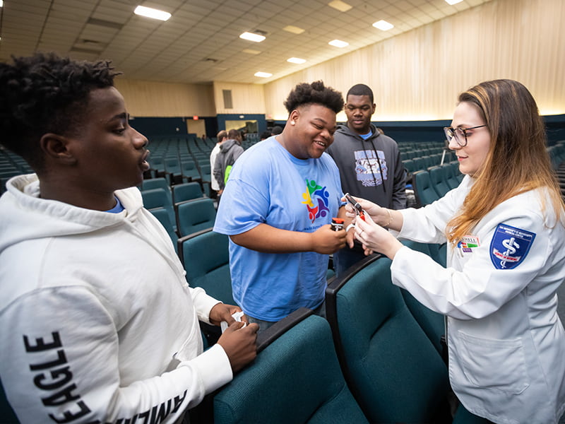 Medical student shows three students how to use opioid overdose rescue device.