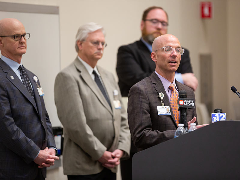 Jones speaking at podium with men behind him.