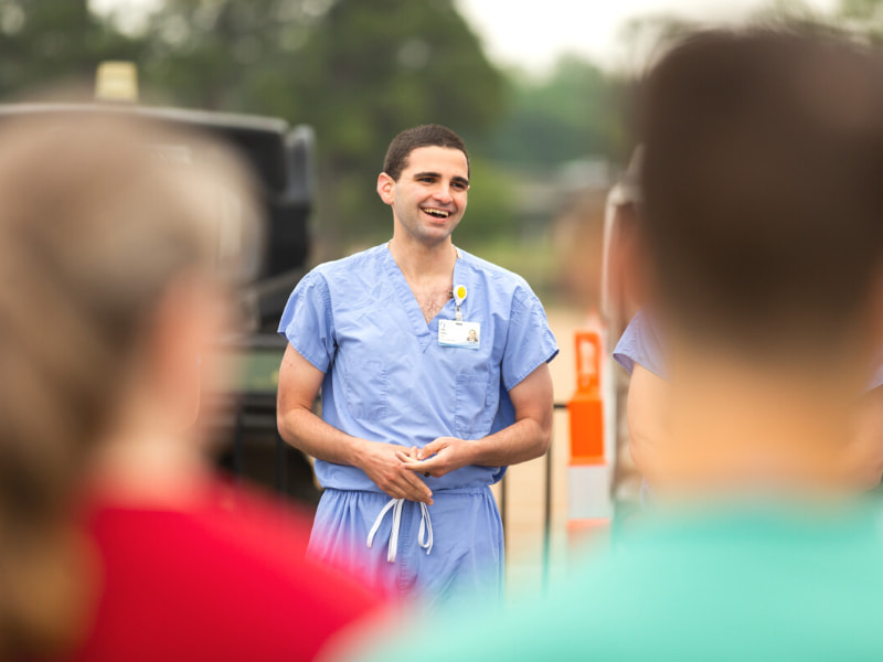 Subhi Younes, School of Graduate Studies in Health Sciences student, shares a laugh with other employees and volunteers after a safety briefing at the fairgrounds.