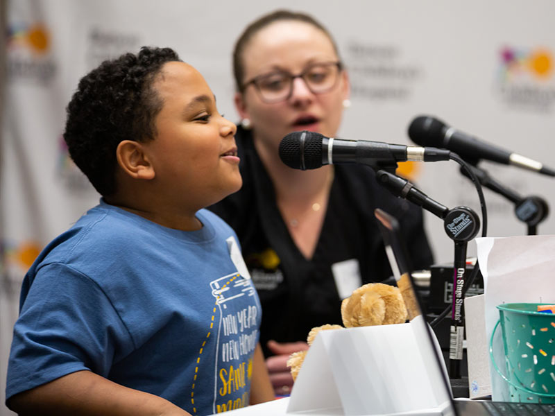 Deuce Bloodsaw speaks on live radio as mom Nikki Cohran, a Children's of Mississippi nurse manager, looks on.