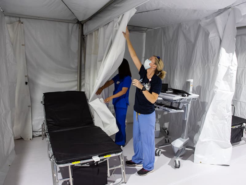 UMMC registered nurse Amanda Laura, left, and licensed practical nurse Brittany Groover put last touches on clinic space in parking Garage B for COVID-19 patients who need to be seen by a caregiver.
