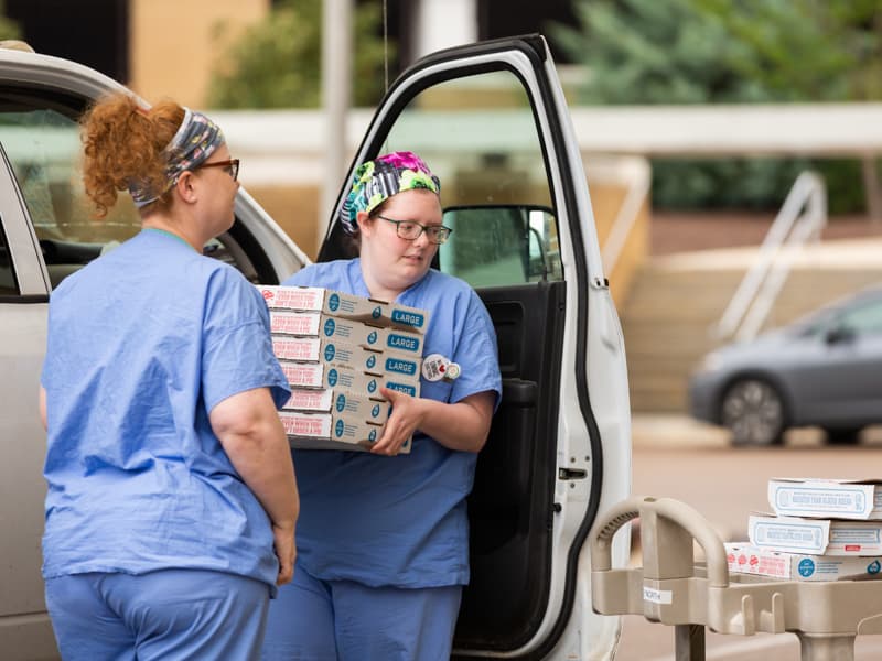 Suzanne Musgrove, left, and Margaret Workman, nurses, unload a stack of pizzas headed for their 2 North unit.