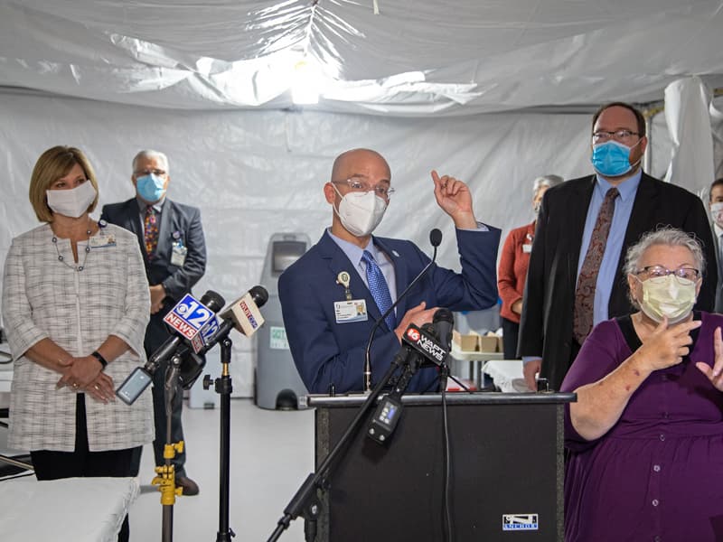 Dr. Alan Jones, center, chair of Emergency Medicine, gives details on the temporary field clinic in Garage B. With him are Dr. LouAnn Woodward, left, vice chancellor for health affairs, and Dr. Jonathan Wilson, right, chief administrative officer.