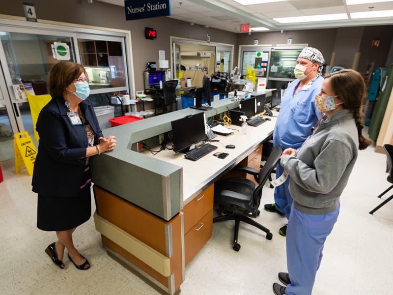 Terri Gillespie, UMMC chief nursing executive and clinical services officer, checks in with registered nurses William Parish and Maggie Luke while making rounds in the Medical ICU, where COVID-19 patients receive care.