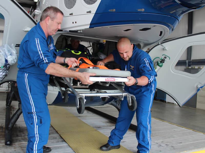 Todd Perry, left, AirCare R.N., and Ben White, paramedic, unload a gurney from the helicopter.