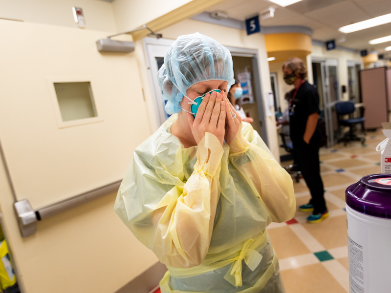 Registered nurse Kailey Thigpen fits her mask before entering the room of a COVID-19 patient in the pediatric ICU who was awaiting test results.