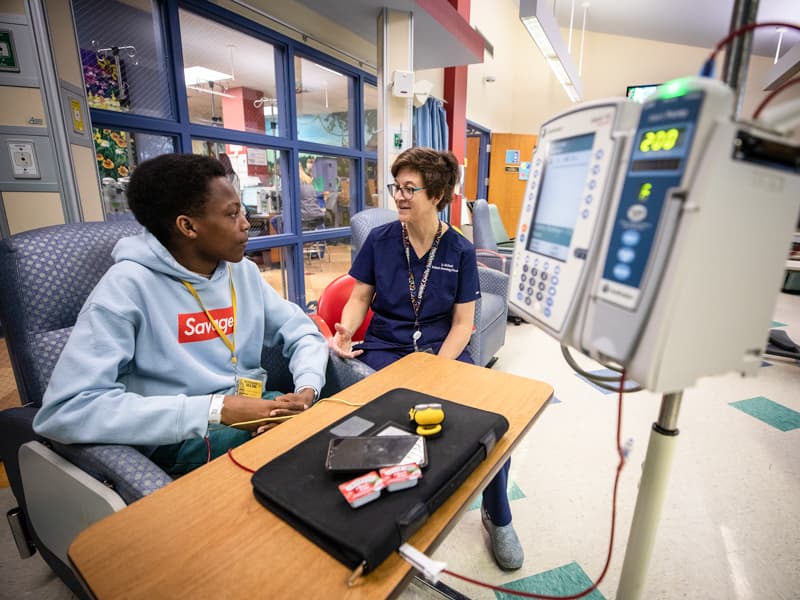 Dr. Melissa McNaull sits with patient Tyler Jackson of Ridgeland during a treatment at Children's of Mississippi's Center for Cancer and Blood Disorders.