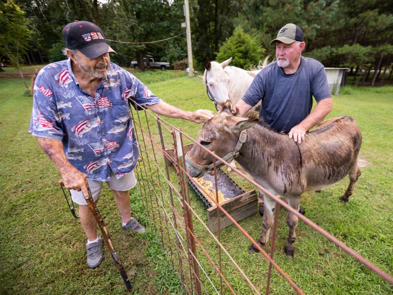 Eupora resident Ray Gustafson, left, is pictured with Bobo the donkey and Gustafson's neighbor, Dale Wilson. AirCare paramedics kept Gustafson from bleeding to death after Bobo bit him in 2017.