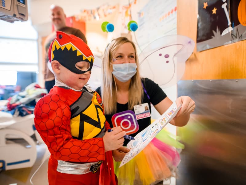 Children's of Mississippi patient Cash Ward of Summit plays a costume scavenger hunt game with child life specialist Tiffany Key, who is dressed as a social (media) butterfly.