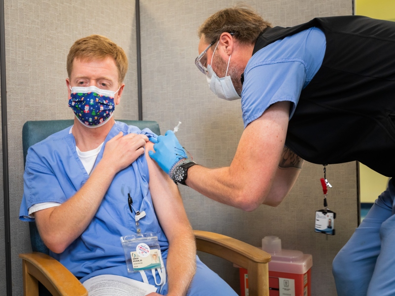 Dr. Jason Parham, director of the Division of Infectious Diseases, takes a post-vaccination photo of 2 North RN John Yu.