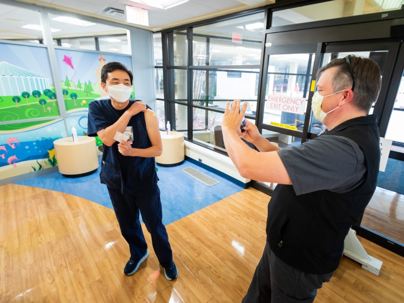 Dr. Jason Parham, director of the Division of Infectious Diseases, takes a post-vaccination photo of 2 North RN John Yu.