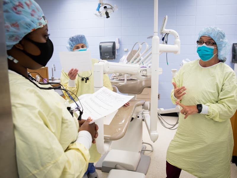 Barbra Brent, right, talks with dental hygiene students Kendra Conley, left and Elizabeth McPhail