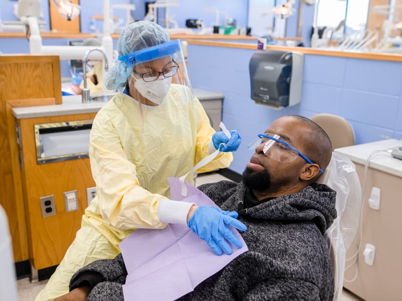Fourth-year dental hygiene student Ashlynn Baney asks patient and U.S. Marine Corps veteran Daniel Bowman of Jackson if he's having any issues with his teeth as part of Bowman's exam during Dental Mission Week.