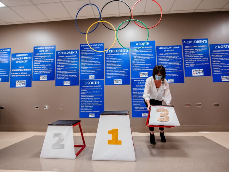 Heather Wise, clinical competency coordinator, places Olympic medal podiums next to the Patient Safety Week display in University Hospital. Employees will receive medals for safety performance at 2:30 p.m. daily.