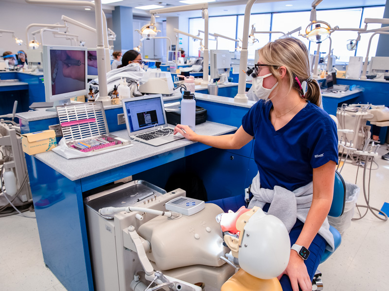 Dental hygiene student Caroline Watson combines instruction from Dr. Sandra Horne with a video lesson in learning how to properly clean a patient's teeth.