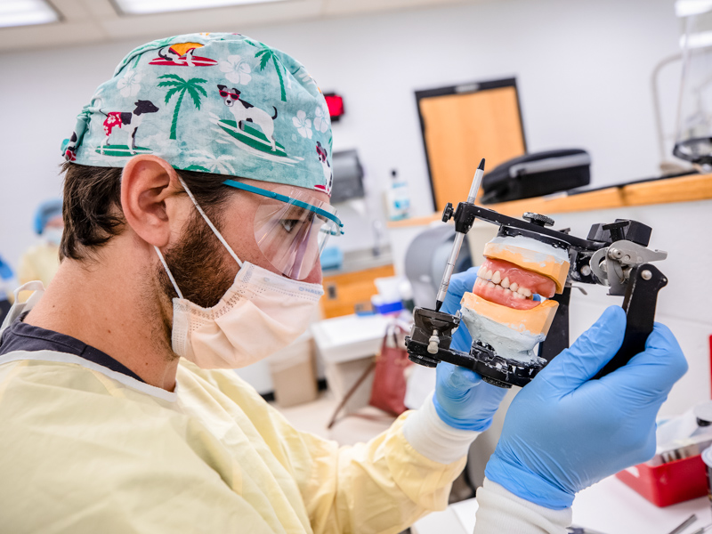 School of Dentistry fourth-year student Trent Johnson checks the bite of Wilbert McGee's new dentures to prepare them for conversion into permanent acrylic dentures.