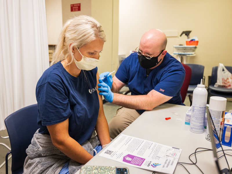 Mary Borrello receives her vaccination from licensed practical nurse Robert Roka in the UMMC vaccine clinic.