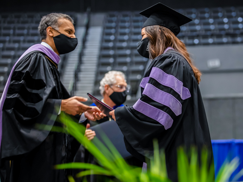 School of Dentistry Dean Sreenivas Koka hands a diploma to 2021 dentistry graduate Taylor Campbell.