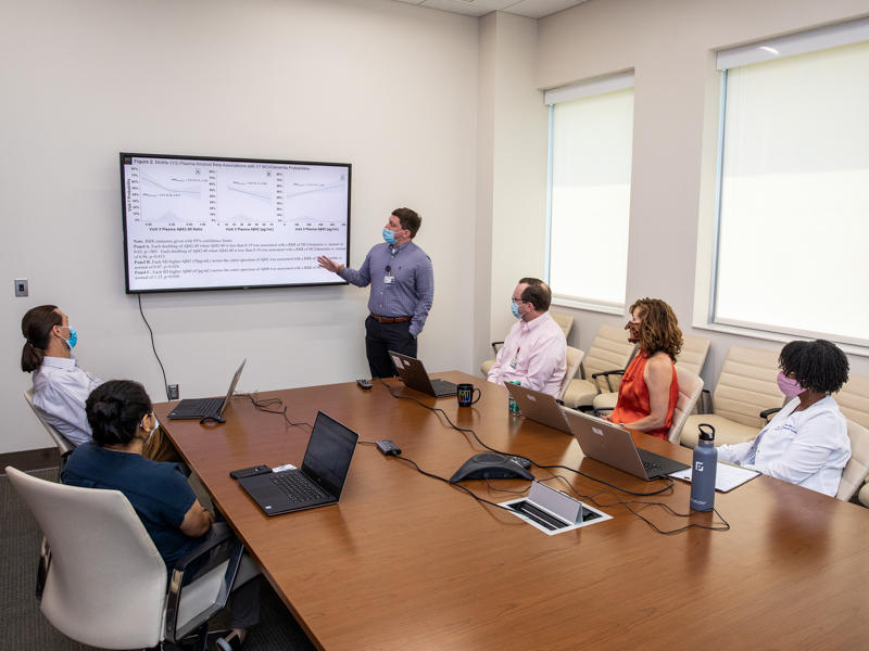 Dr. Kevin Sullivan, assistant professor, Neuroepidemiology, goes over research with MIND Center researchers, from left, seated, Dr. Srishti Shrestha, assistant professor, Dr. Michael Griswold, professor & director, MIND Center Science, Evidence, & Technology Research Core,Chad Blackshear, Biostatistician, Data Sciences and The MIND Center, Dr. B. Gwen Windham, Professor & Director, Neuroepidemiology Research Core, and Stacee Naylor, MSN, RN, CCRP, Director of Clinical Research Operations.